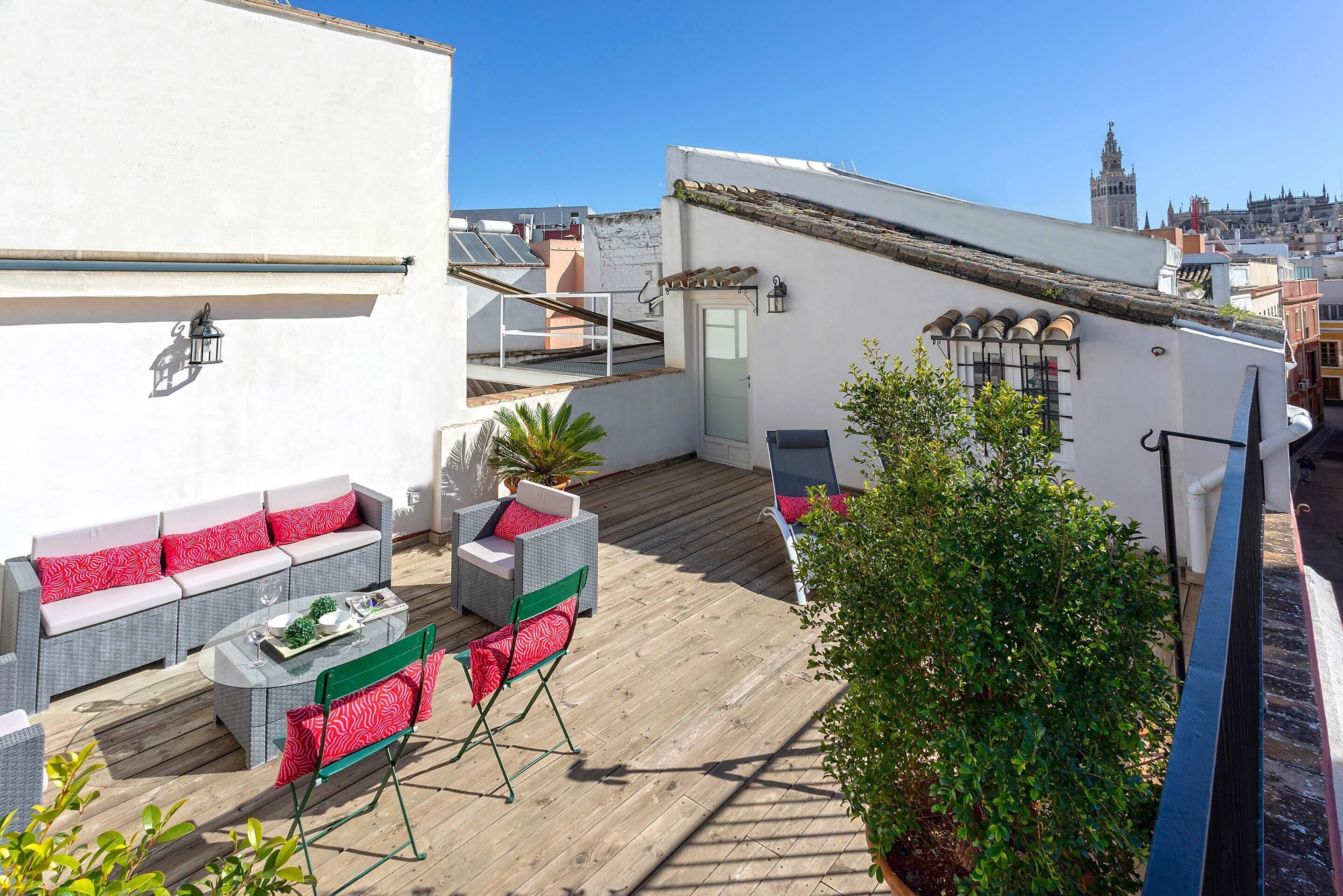 Eine Dachterrasse mit Sitzgelegenheiten im Freien, einem Tisch und einem Blumentopf.