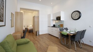 Apartamento moderno com área de jantar, cozinha compacta e sofá verde.
