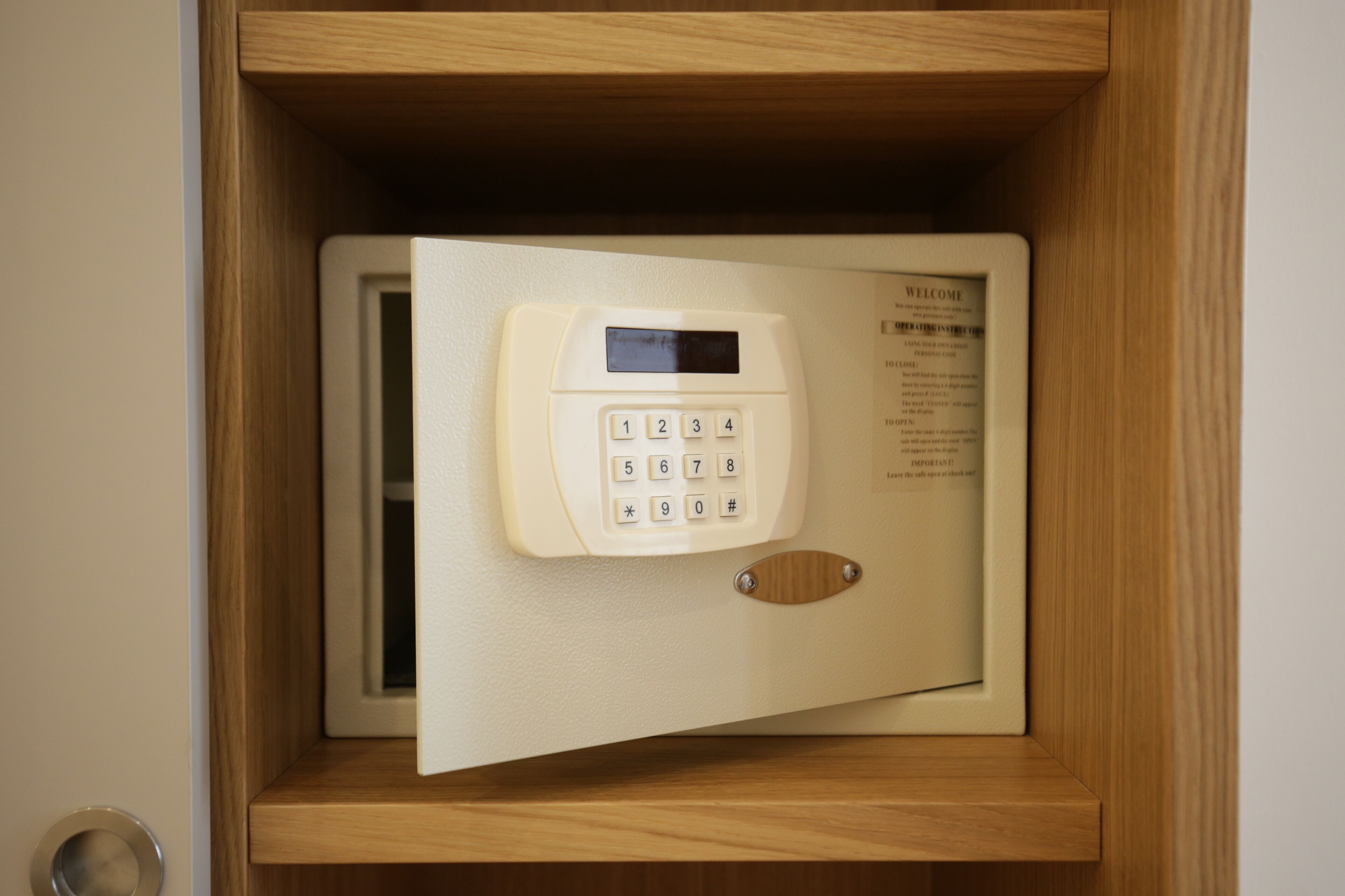 A safe with a keypad and a welcome message inside a wooden cabinet.