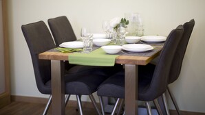 Mesa de jantar posta com pratos brancos, copos e um caminho de mesa verde.