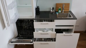 Cozinha compacta com lava-louças embutida, pia e bancada de madeira.