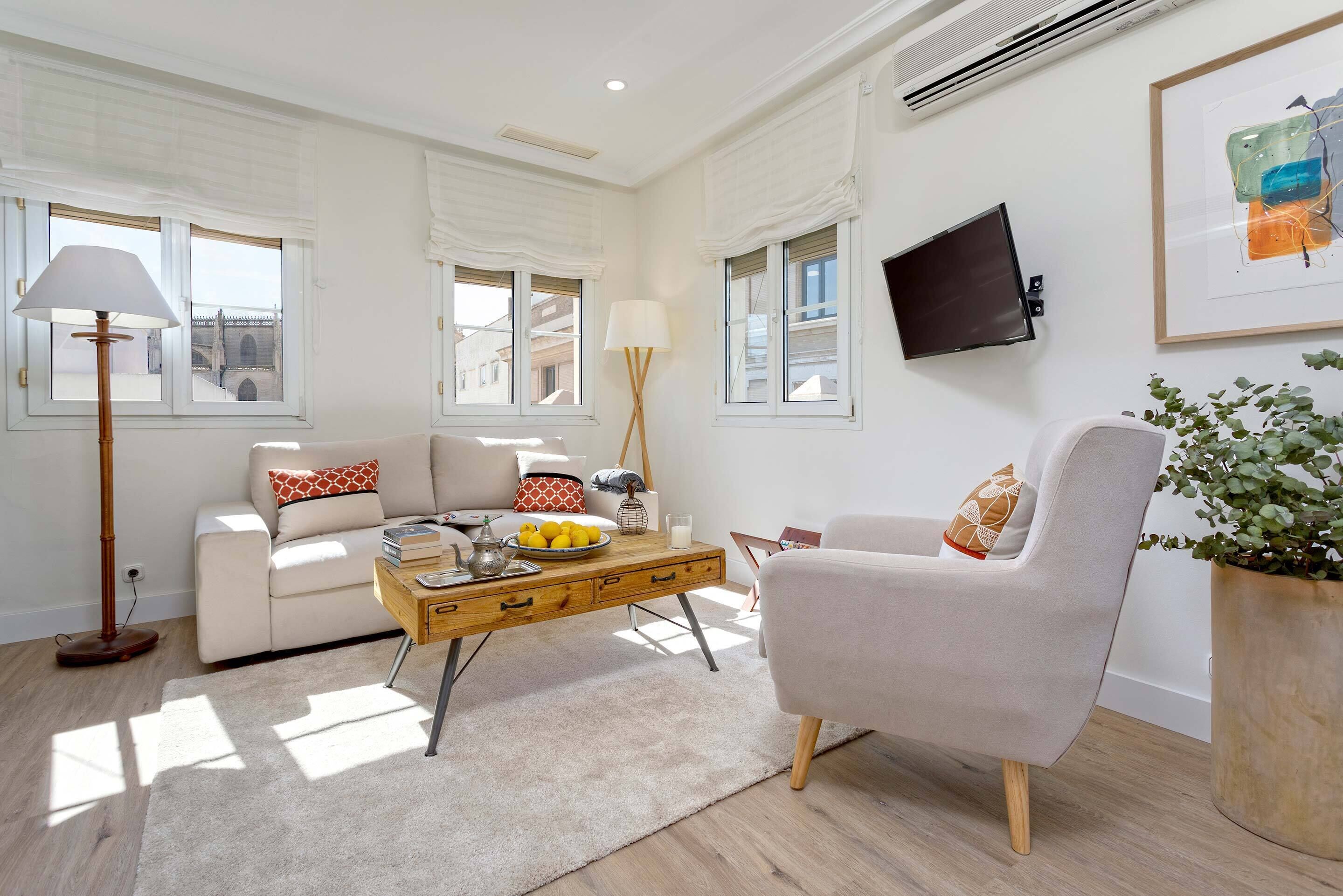 A modern living room with a sofa, armchair, coffee table, and a potted plant.