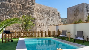 A swimming pool with a wooden deck, a wooden fence, and lounge chairs. - Genteel Home San Nicolas (Granada)