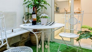 A small patio area with a round table and two chairs, a potted plant, a bottle of wine, and two wine glasses. - Genteel Home Galera I (Seville)