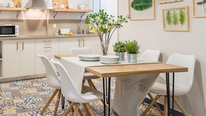 Une cuisine moderne avec des meubles blancs, un four à micro-ondes et une table en bois dressée pour le repas.