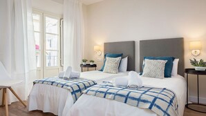 Une chambre d’hôtel avec deux lits, une petite table, une chaise et une fenêtre avec des rideaux.