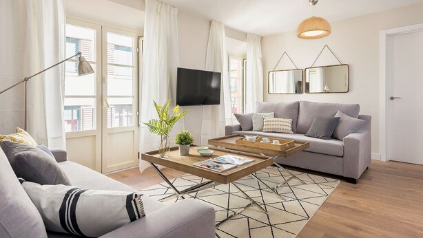 Un salon moderne avec un canapé, une table basse et un téléviseur.