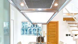 A modern dining area with a glass table, chairs, and a view of a cityscape through a large window. - Genteel Home Real de la Carreteria (Seville)
