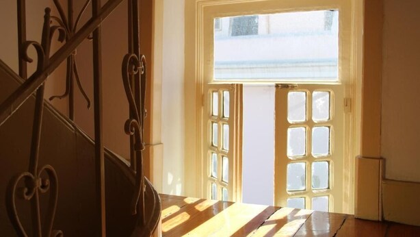 Une pièce avec un plancher en bois, un escalier en métal et une porte dotée d’une fenêtre.