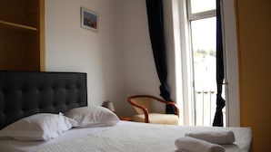 Une chambre d’hôtel avec un lit, une chaise, une fenêtre et une porte.