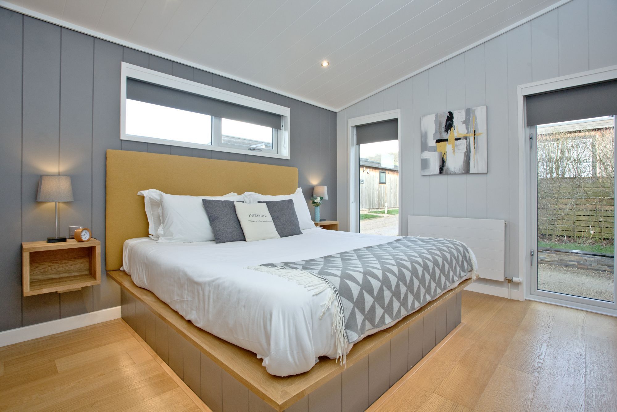 Une chambre moderne avec un grand lit, des tables de chevet, une fenêtre et une vue sur l’extérieur.
