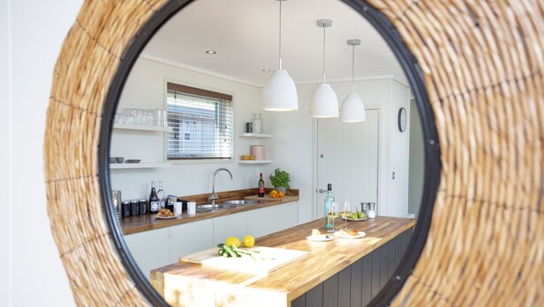 Een keuken met een ronde spiegel, houten aanrechtbladen en hangende hanglampen.