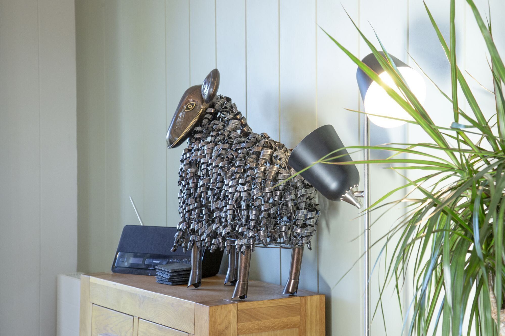 A sculpture of a figure with a hat and a lamp on a wooden surface.