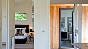 A modern bedroom with a bed, bedside table, and a view of the bathroom. - Mulberry Lodge, Strawberryfield Park (Cheddar)