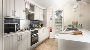 Una cocina moderna con armarios blancos, horno empotrado, microondas y una pequeña isla con tostadora.