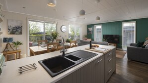 Una cocina moderna con una isla grande, un comedor con mesa y sillas, y una sala de estar con sofá y televisor.