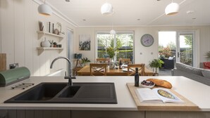 Una cocina moderna con una isla grande, un comedor con vistas y una sala de estar con sofá y mesa.