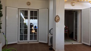 Un patio cubierto con puertas de vidrio correderas, un ventilador y una manguera en el suelo.