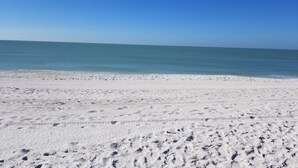 Una playa de arena blanca y cielo azul despejado.