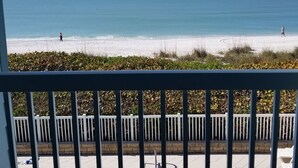 Un balcón con vista a una playa y una piscina.