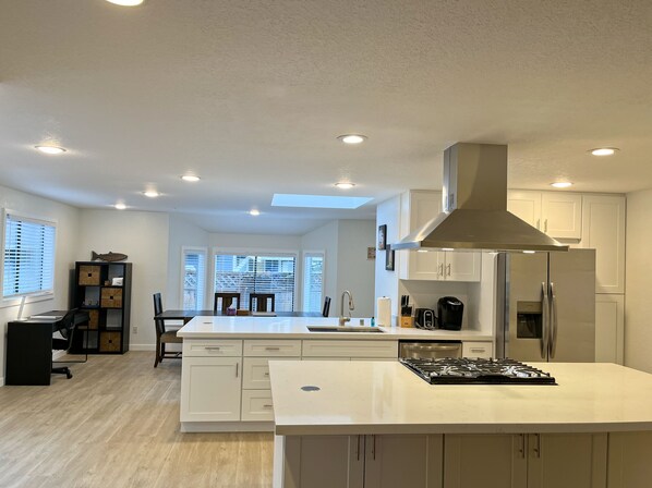 Una cocina moderna con armarios blancos, una isla central y una campana extractora de acero inoxidable.