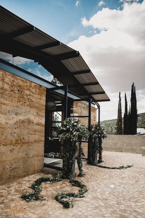 Un edificio moderno con fachada de piedra, un acceso cubierto y un patio adoquinado.