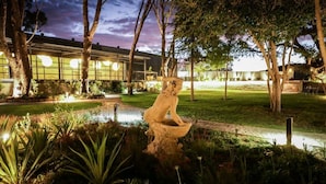 A garden with a water feature and a building in the background. - Droombos (Windhoek)