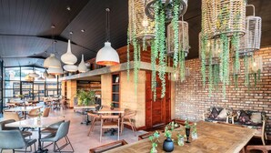A spacious restaurant with high ceilings, hanging wicker chandeliers, and a large wooden table in the center. - Droombos (Windhoek)