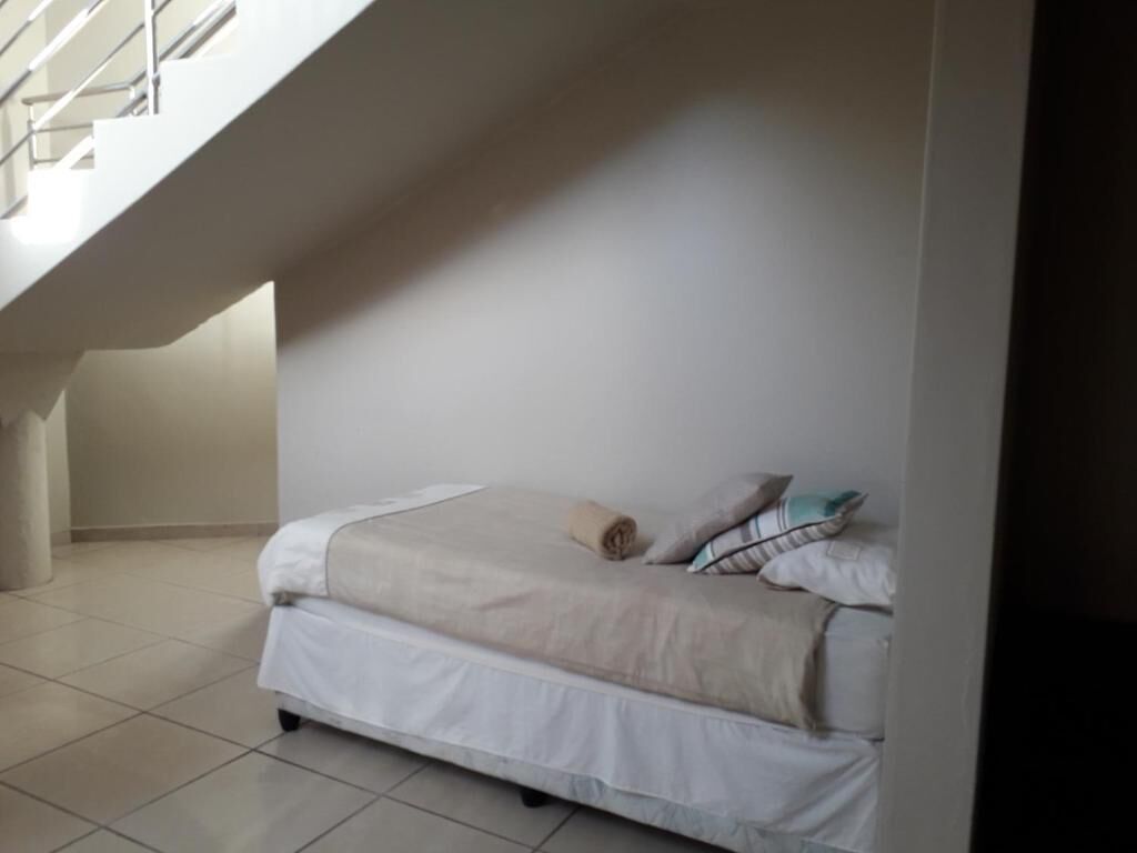 A bedroom with a bed, pillows, and a rolled towel.