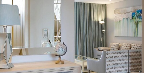Una sala de estar moderna con un sofá, un globo terráqueo sobre una mesa y un ventanal con cortinas.