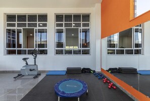 Un gimnasio con equipo de ejercicio, que incluye una bicicleta estática, un trampolín y mancuernas.