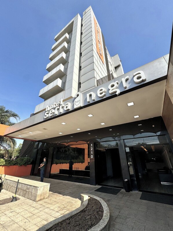 A hotel entrance with a modern facade, a visible address sign, and a landscaped area in front. - Hotel Serra Negra (Betim)