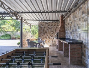 An outdoor patio area with a foosball table, a brick fireplace, and a covered seating area. - Hotel Serra Negra (Betim)
