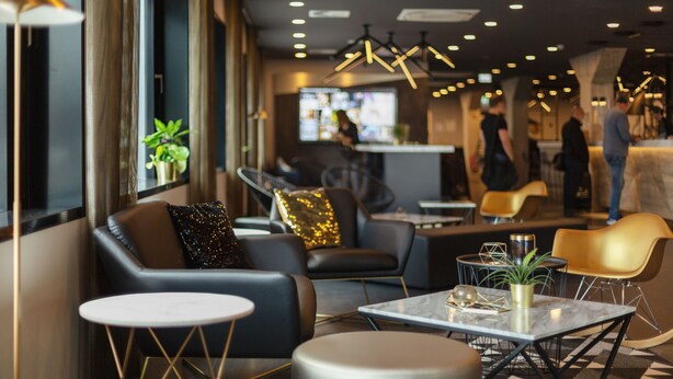 A modern lounge area with leather seating, a marble table, and ambient lighting. - Holiday Inn - the niu, Coin Frankfurt Ostend by IHG (Frankfurt)