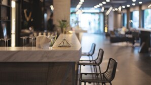 A modern bar area with a marble countertop, a geometric glass sculpture, and a row of chairs. - Holiday Inn - the niu, Coin Frankfurt Ostend by IHG (Frankfurt)