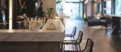 A modern bar area with a marble countertop, a geometric glass sculpture, and a row of chairs.