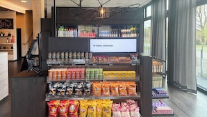 Ett bord med olika sorters chips och snacks, ett digitalt välkomstmeddelande och utsikt över omgivningen genom stora fönster.