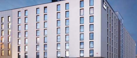A modern hotel building with a flat facade, numerous windows, and a sign indicating it is 'The Niu'.