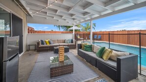 A covered patio area with a pool, outdoor seating, and a refrigerator. - Family Retreat w/ Theater, Pool & Outdoor Dining (Chula Vista)