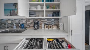 A kitchen with white cabinets, a tiled backsplash, and a dish rack. - Family Retreat w/ Theater, Pool & Outdoor Dining (Chula Vista)