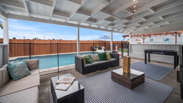 An outdoor patio area with a pool, seating, and a foosball table. - Family Retreat w/ Theater, Pool & Outdoor Dining (Chula Vista)