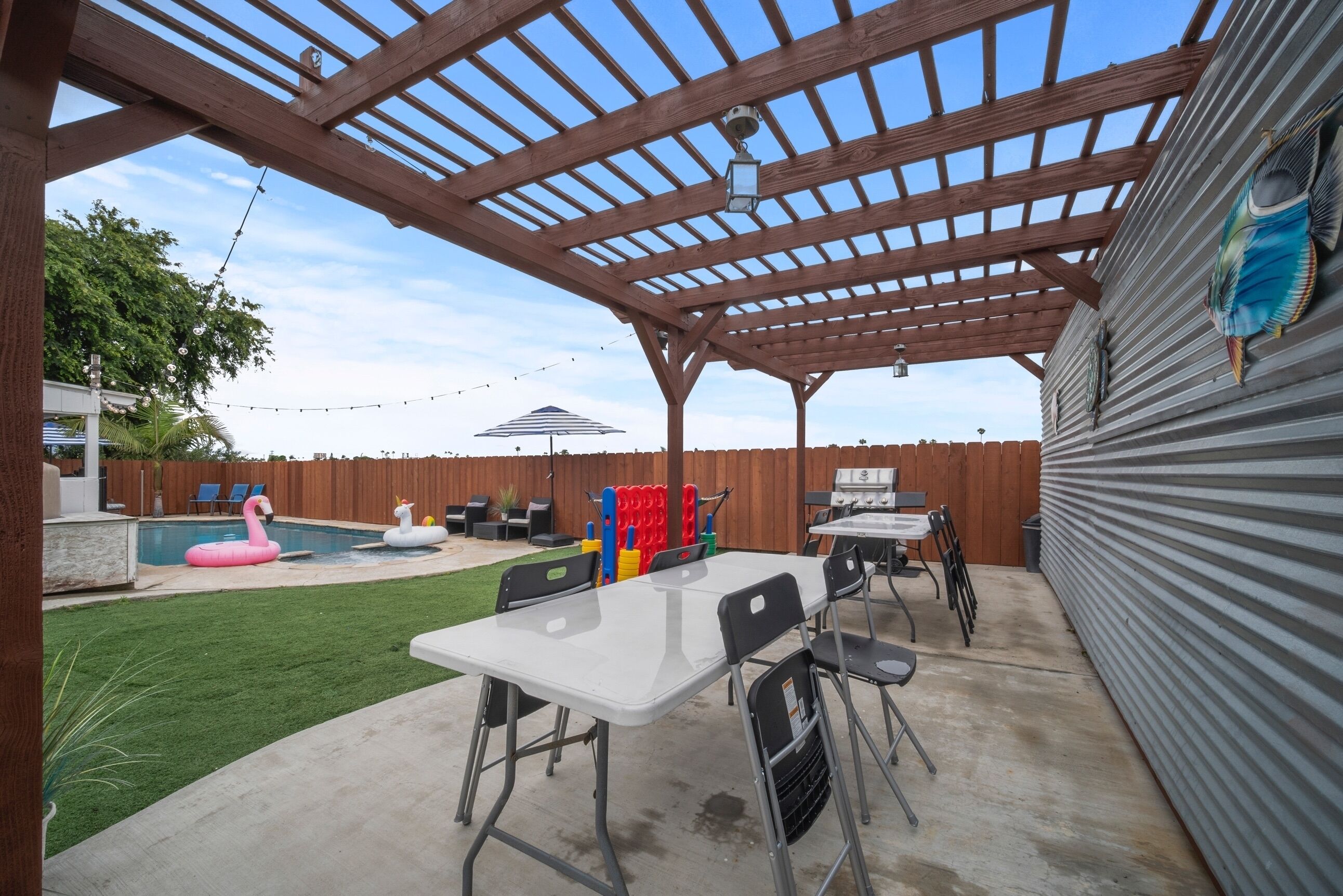 Un patio techado con piscina, mobiliario exterior y valla de madera.