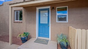 A house with a blue door, a welcome mat, and two potted plants. - 4bd,2ba Remodeled North Valley Home w/ large yard (Los Ranchos De Albuquerque)