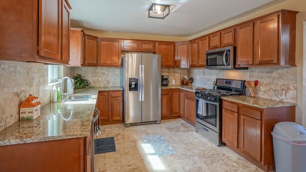 A kitchen with wooden cabinets, stainless steel appliances, granite countertops, and a tiled floor. - 4bd,2ba Remodeled North Valley Home w/ large yard (Los Ranchos De Albuquerque)