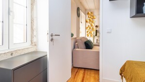 Una habitación con piso de madera, un sofá, una mesita y una ventana con vistas.