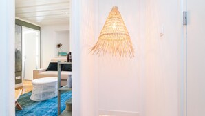 Un interior moderno con una lámpara tejida, un sillón blanco redondo y una alfombra azul.