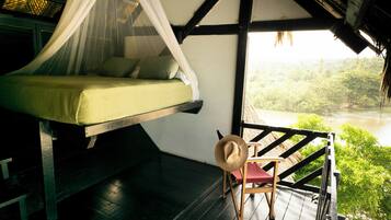 Una cama con dosel, una silla y vistas a un río.