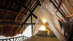 Una cama con dosel, vigas de madera y techo tejido.
