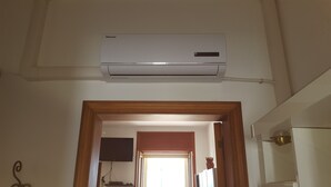 A room with a mounted air conditioner, a wooden-framed doorway, and a visible television set. - holiday home 150 meters from the sea (Lido Marini)