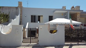 A modern house with a white exterior, a stone chimney, and a black metal gate. - holiday home 150 meters from the sea (Lido Marini)
